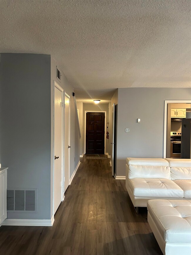 Hall with dark wood-style floors, visible vents, a