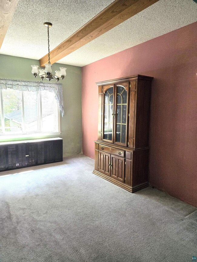 Unfurnished dining area featuring beam ceiling, a 