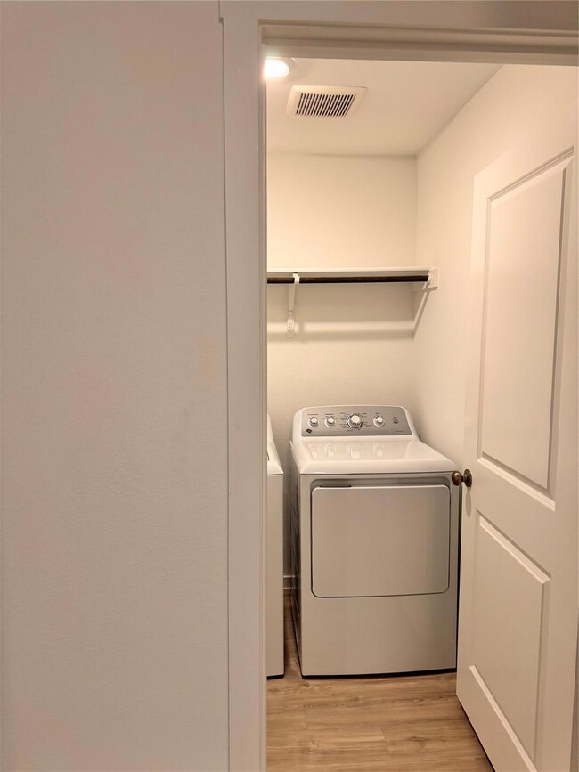 Clothes washing area with light hardwood / wood-style flooring and washer and dryer