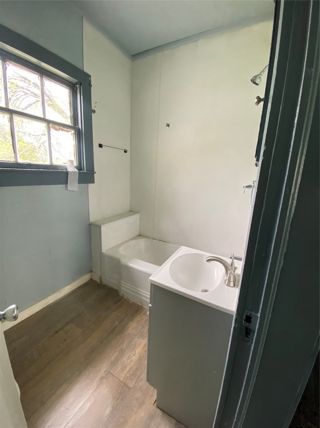 Bathroom featuring shower / tub combination, wood-type flooring, and vanity