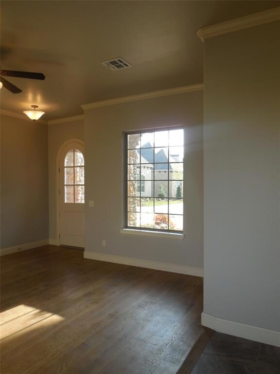 Spare room featuring ornamental molding, dark wood-style floors, and ceiling fan