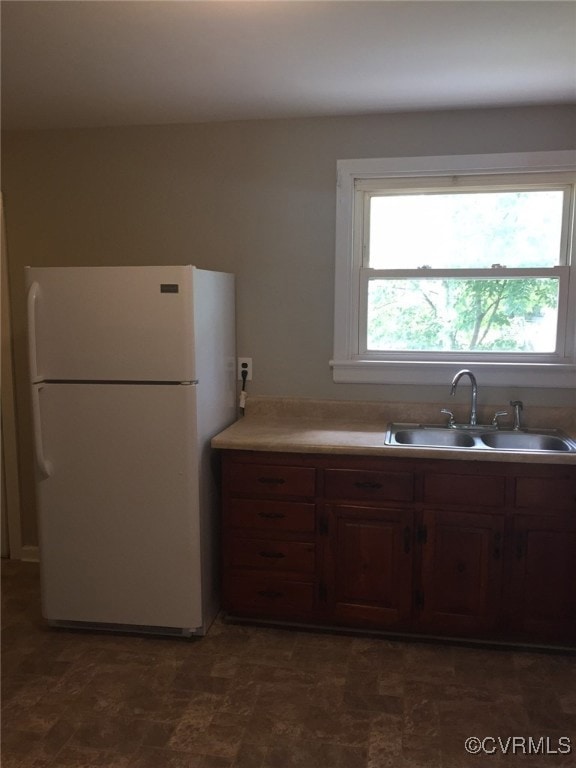 Kitchen featuring freestanding refrigerator, a sin