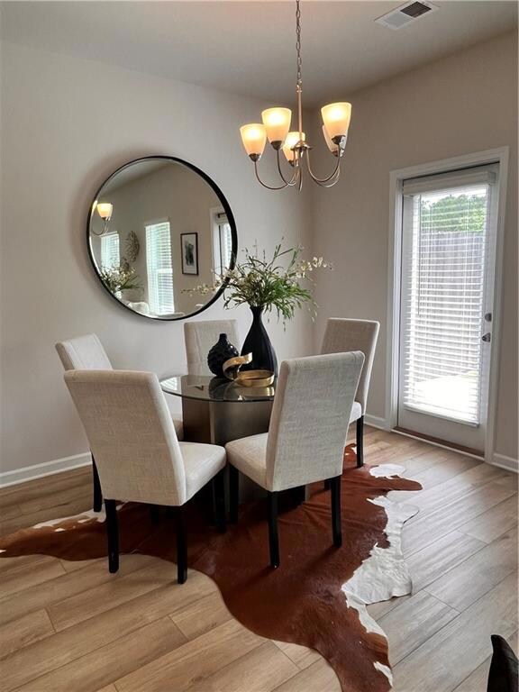 Dining room featuring a chandelier, light wood-type flooring, and baseboards