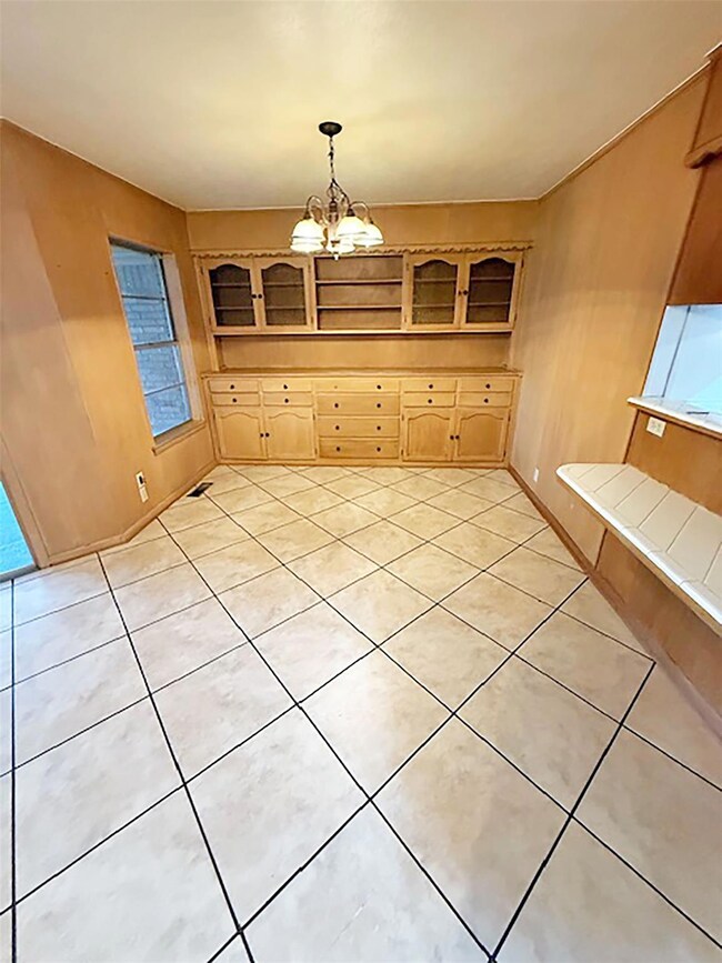 Unfurnished dining area featuring an inviting chandelier and light tile patterned floors