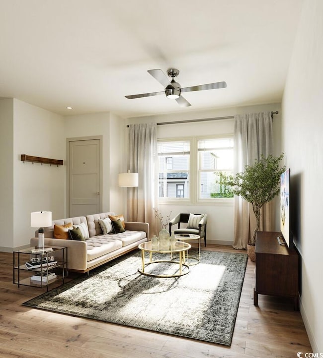 Sitting room featuring ceiling fan and light hardw