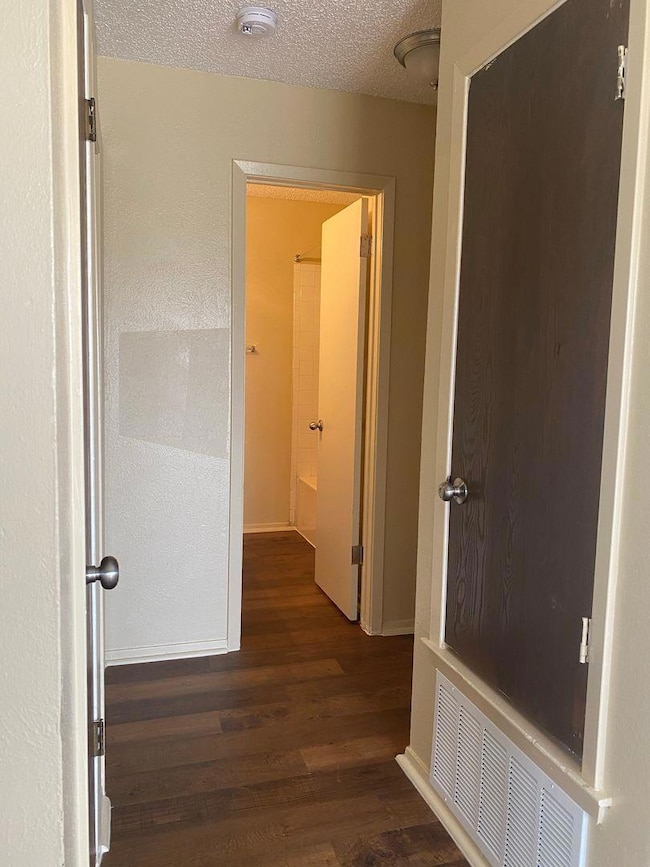 Hallway featuring a textured ceiling, visible ven