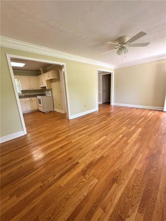 Unfurnished living room with ornamental molding, a textured ceiling, light wood finished floors, ceiling fan, and baseboards