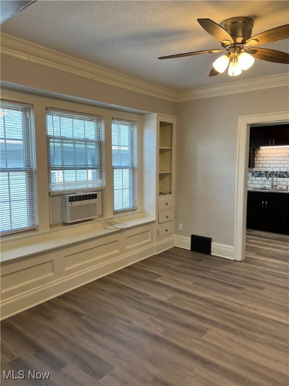Unfurnished room with visible vents, ornamental molding, a sink, dark wood finished floors, and baseboards