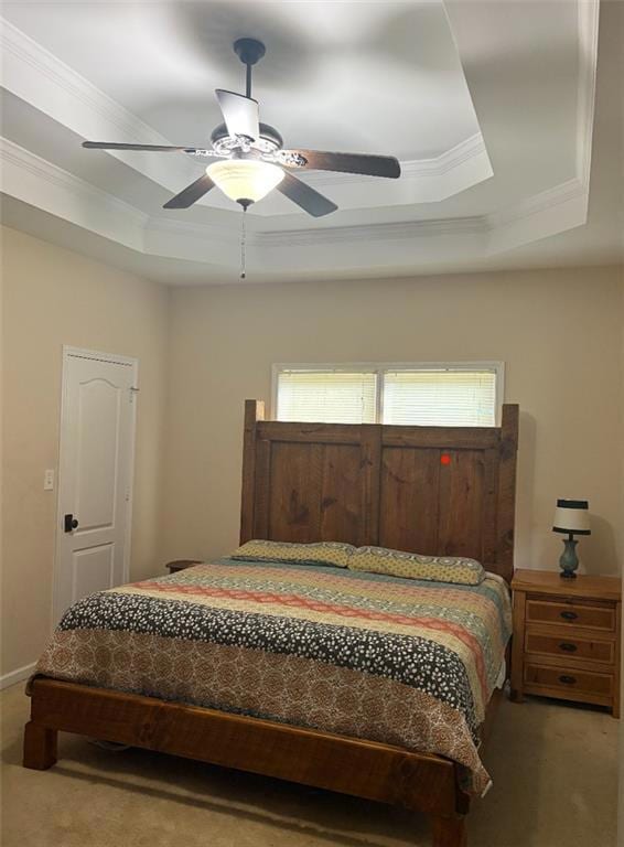 Bedroom featuring a tray ceiling, carpet, crown molding, multiple windows, and a ceiling fan