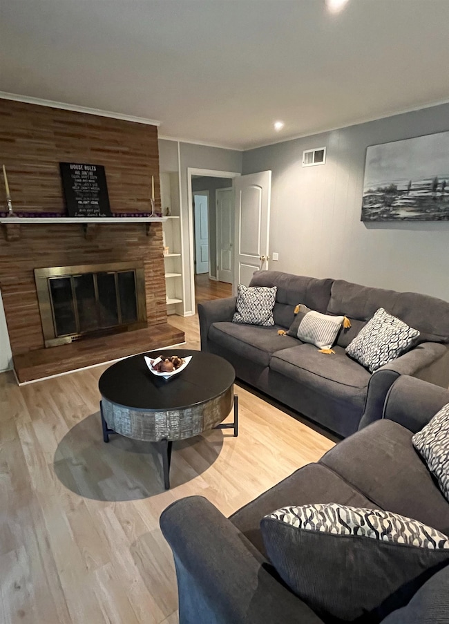 Den with a glass covered fireplace, light wood-style flooring, and recessed lighting