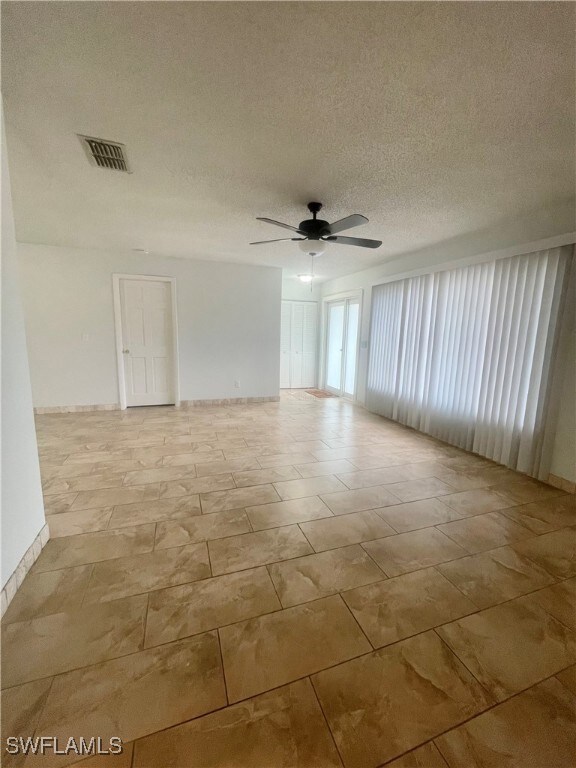 Unfurnished room with ceiling fan and a textured ceiling