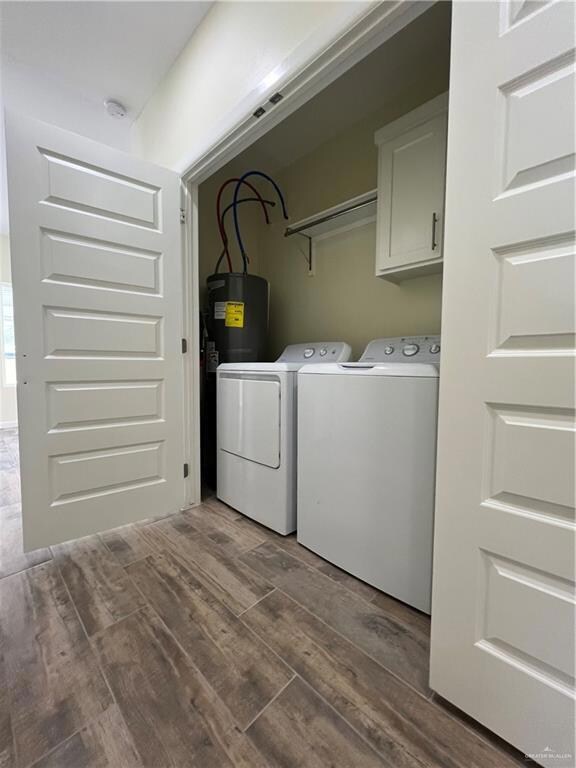Clothes washing area featuring washing machine and dryer, water heater, and wood-type flooring
