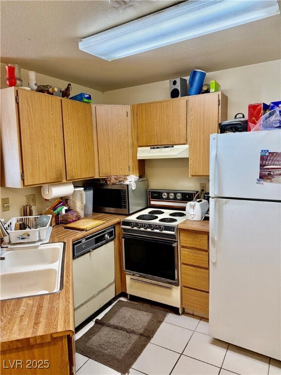 Kitchen with a sink, a textured ceiling, under cab