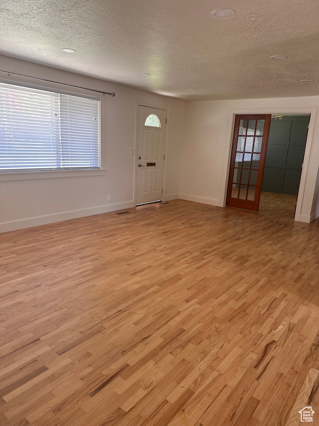 Foyer entrance with light wood finished floors and a textured ceiling