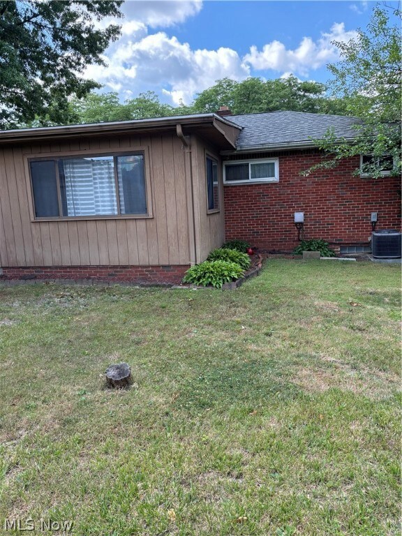 View of property exterior with central AC and a yard