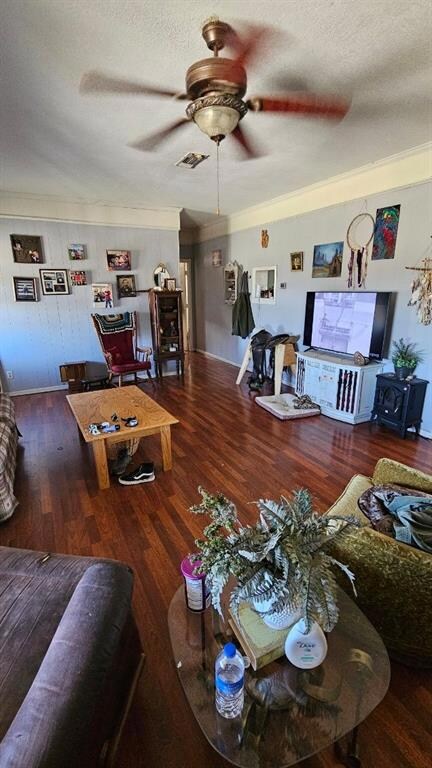 Living room with ornamental molding, a textured ceiling, ceiling fan, and dark wood-type flooring