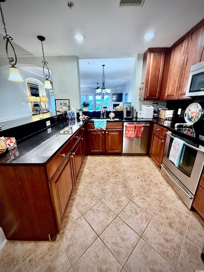 Kitchen with light tile patterned floors, stainless steel appliances, hanging light fixtures, recessed lighting, and dark stone countertops