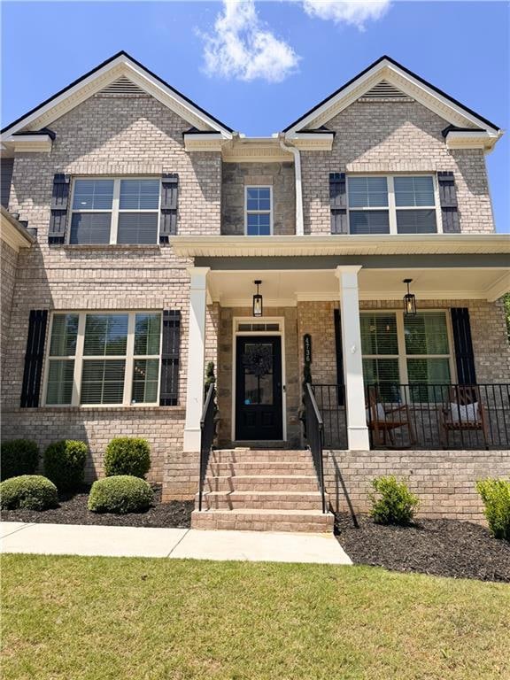 View of front of home with brick siding, covered p