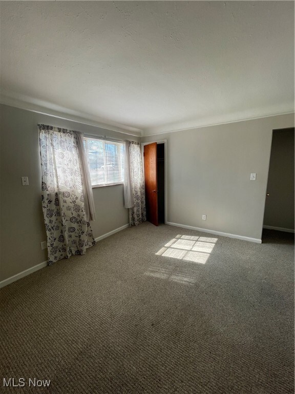 Carpeted empty room featuring baseboards