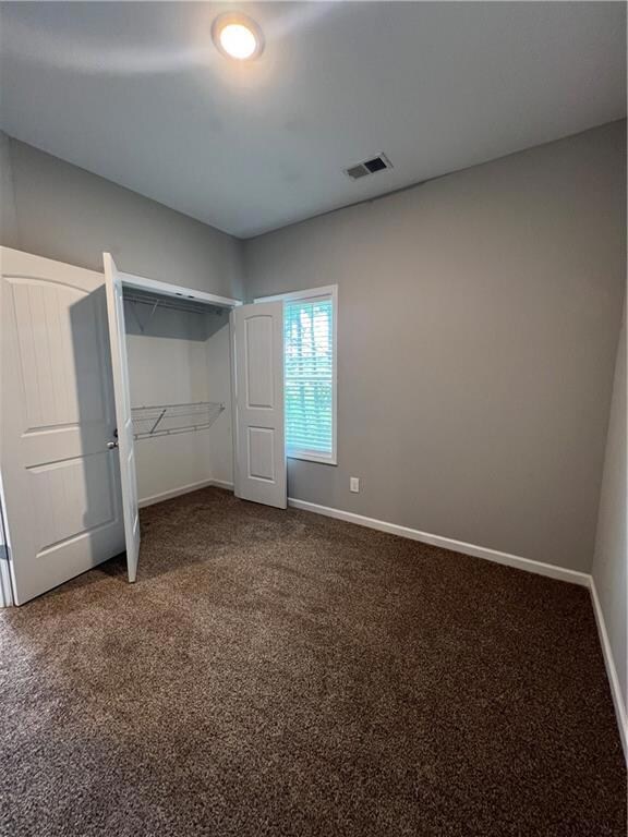 Unfurnished bedroom with dark colored carpet and a closet