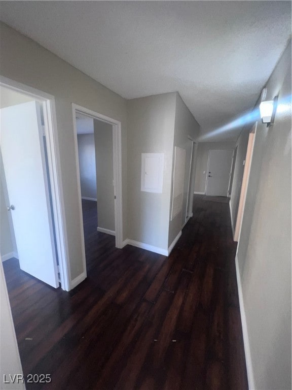 Hallway with dark wood finished floors and baseboa