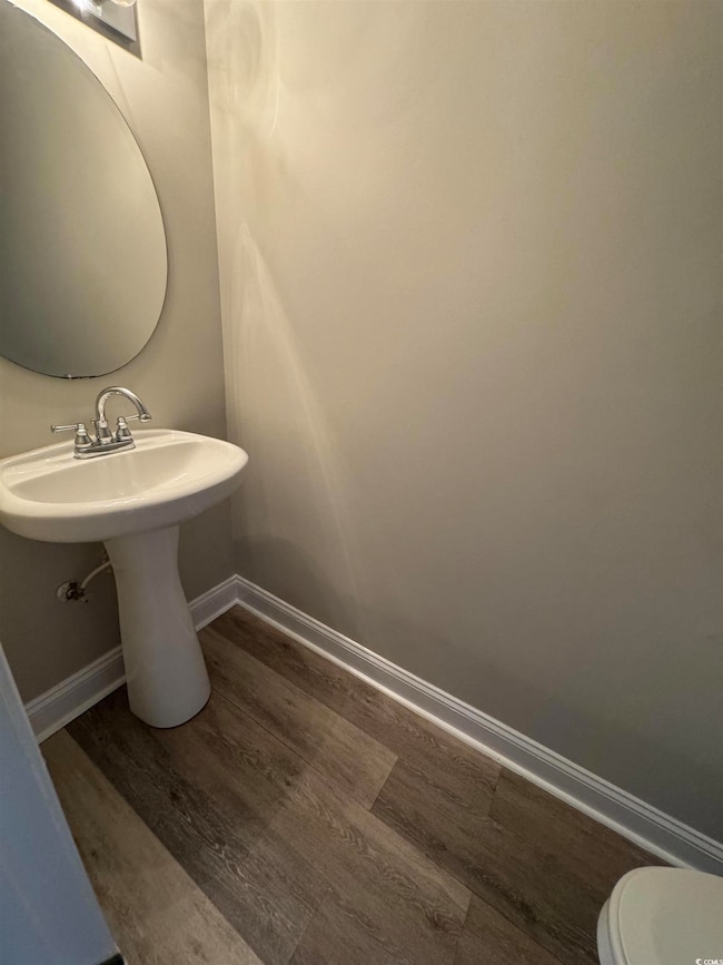 Bathroom with baseboards, wood finished floors, an