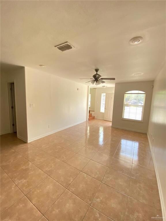 Spare room featuring visible vents, a ceiling fan, baseboards, and light tile patterned floors