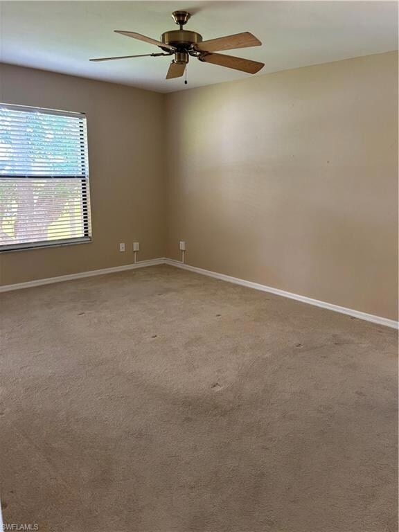 Spare room with light colored carpet, ceiling fan, and baseboards