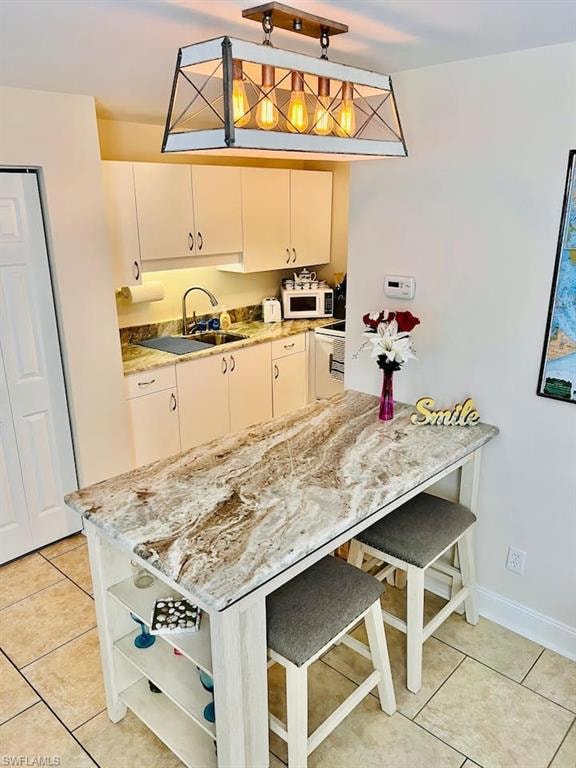 Kitchen featuring white appliances, open shelves, light tile patterned floors, a sink, and cream cabinetry