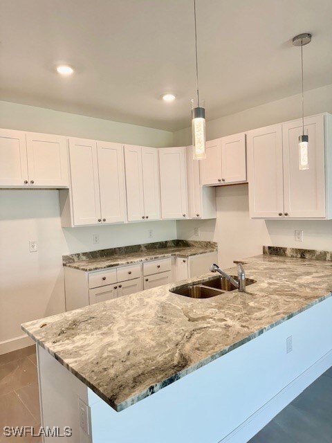 Kitchen featuring white cabinetry, light stone cou