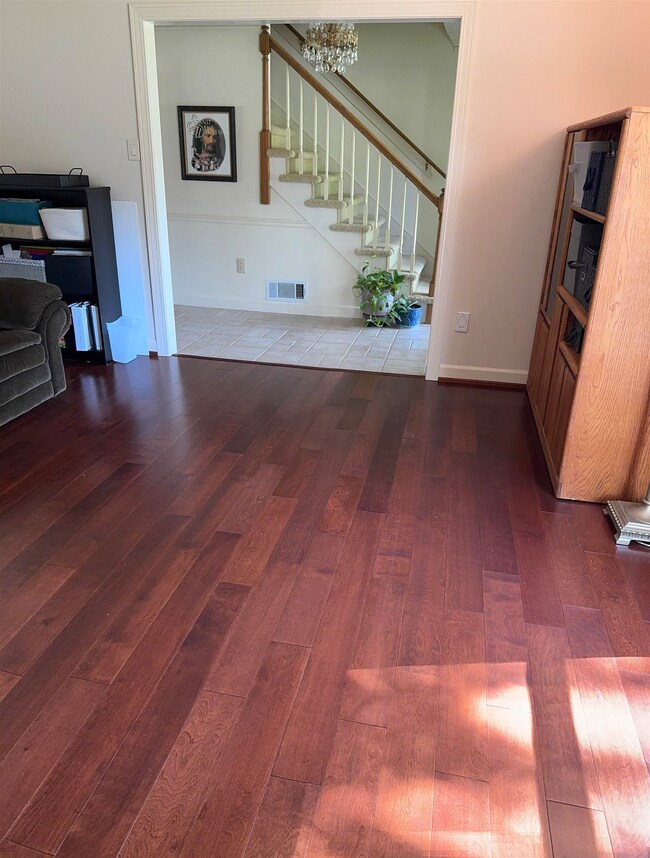 Unfurnished living room with wood finished floors, stairway, and a chandelier