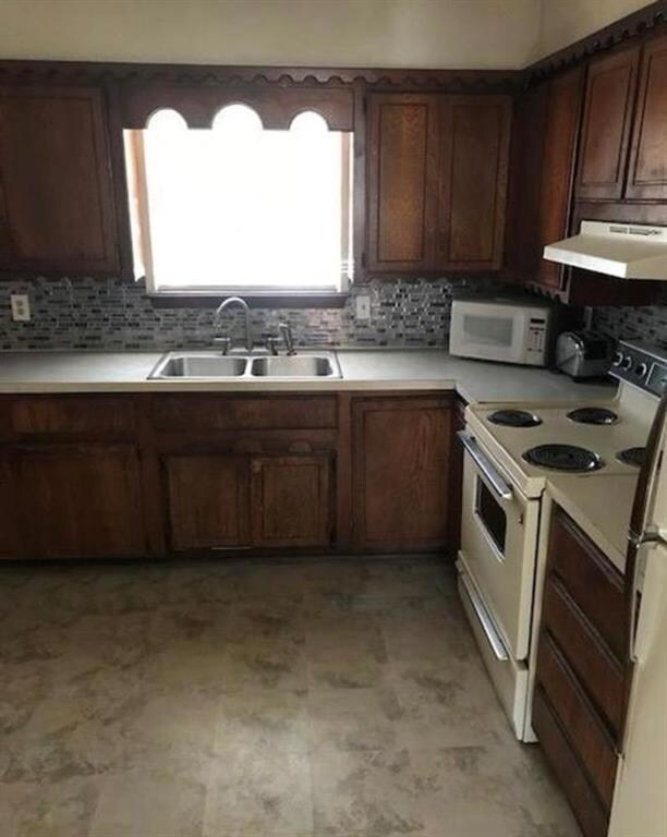 Kitchen featuring tasteful backsplash, white appli
