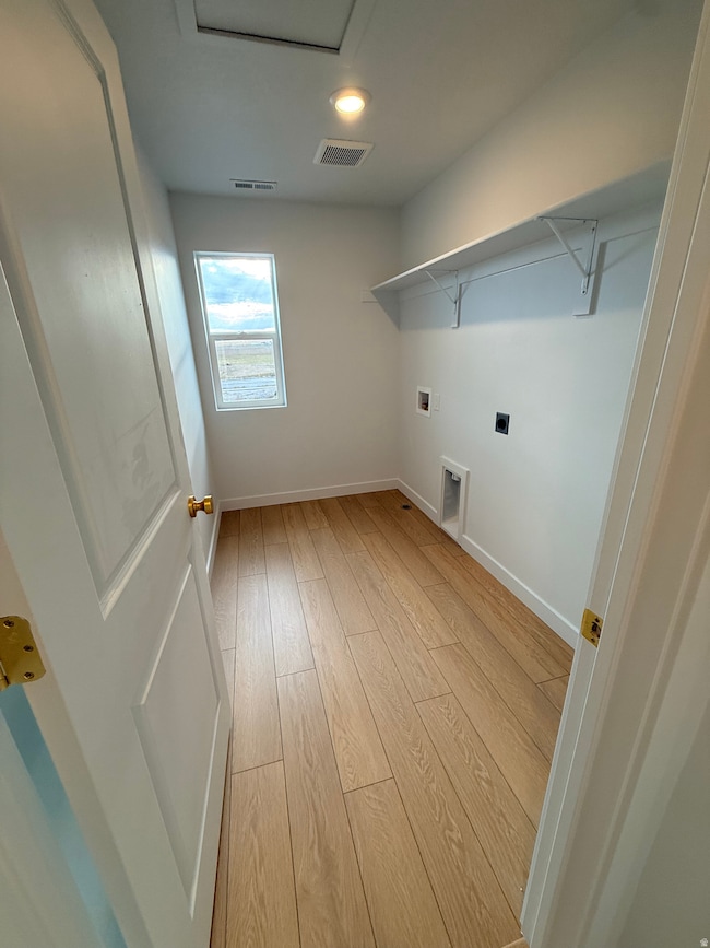 Laundry area featuring light wood-style floors, hookup for an electric dryer, and washer hookup