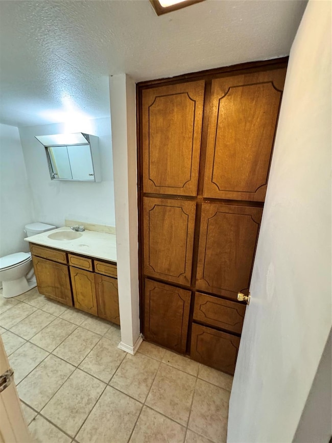 Bathroom featuring tile floors, vanity, toilet, an