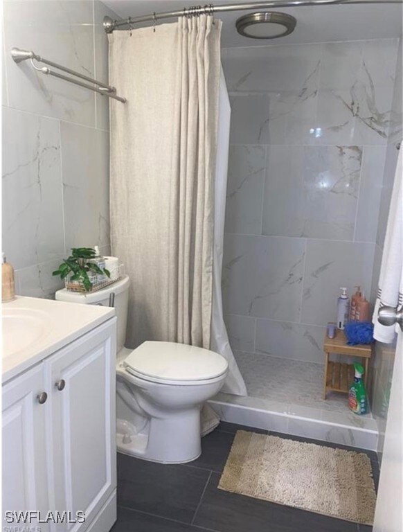 Bathroom with a stall shower, vanity, and dark tile patterned flooring