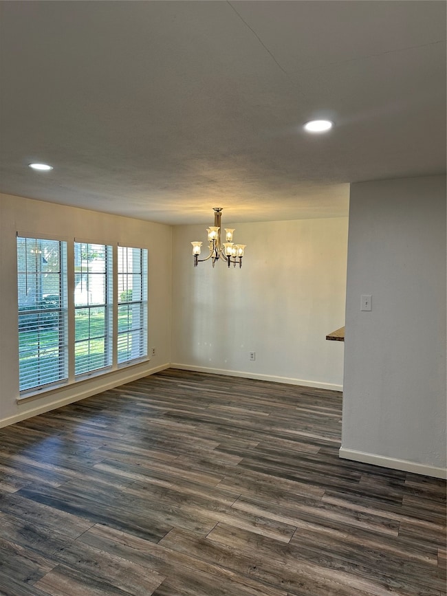 Unfurnished room with recessed lighting, a chandelier, and dark wood-style flooring