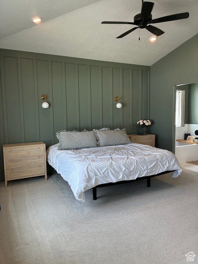 Bedroom featuring a decorative wall, a textured ceiling, lofted ceiling, carpet, and ceiling fan
