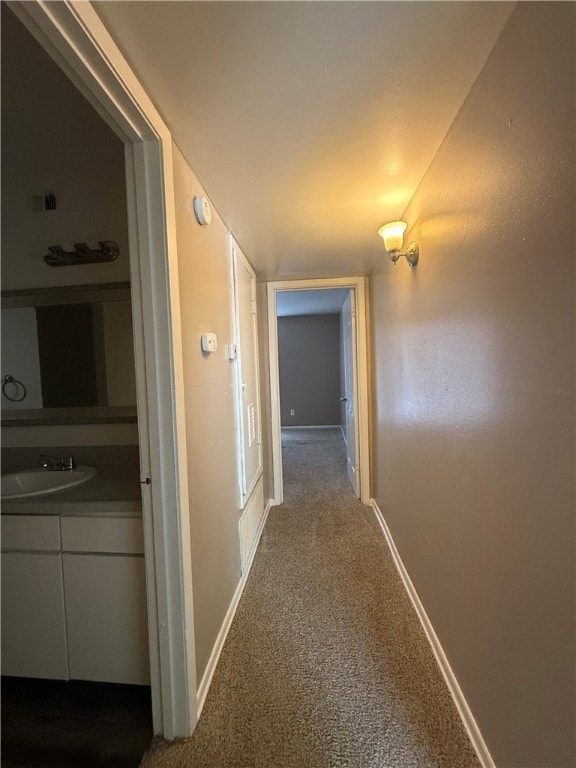 Corridor with a sink and dark carpet