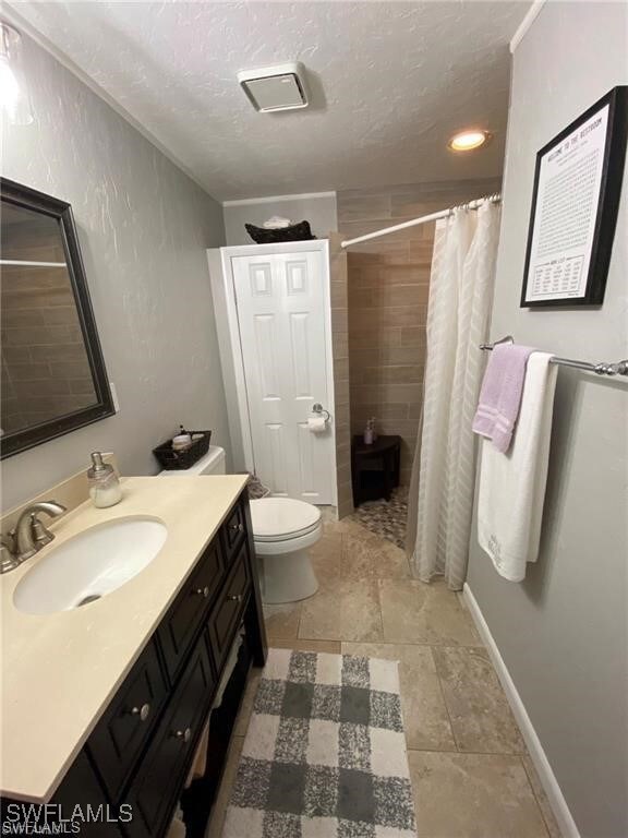 Bathroom featuring vanity, toilet, a textured ceil