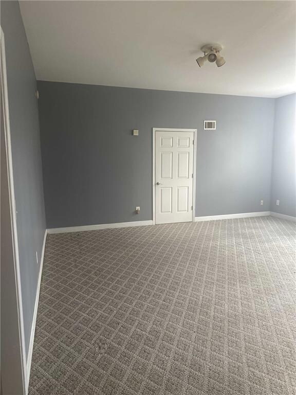 Spare room featuring carpet floors, visible vents,