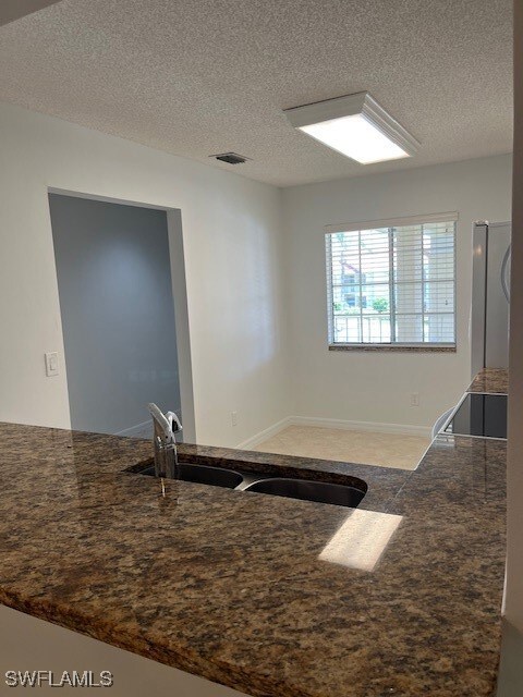 Kitchen with a textured ceiling, refrigerator, sin