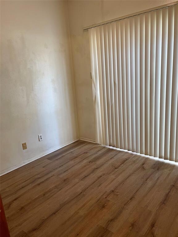 Spare room with baseboards and wood finished floo
