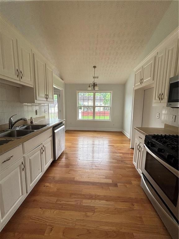 Kitchen with stove, dishwashing machine, a sink, white cabinetry, and a textured ceiling