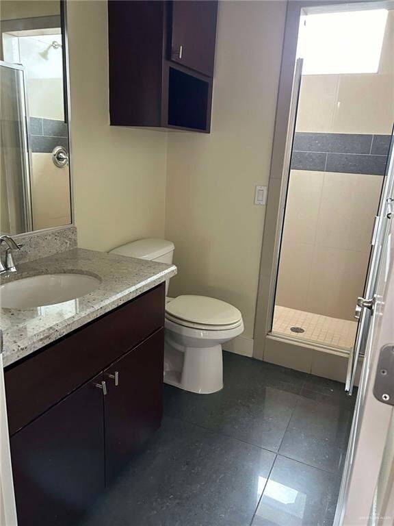 Full bathroom with toilet, a stall shower, vanity, and tile patterned floors