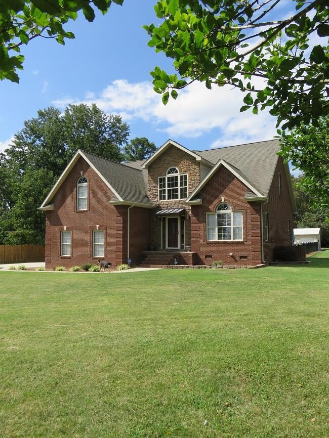 Side angle with wonderful landscaping, design sidewalks, huge yard and inground pool
