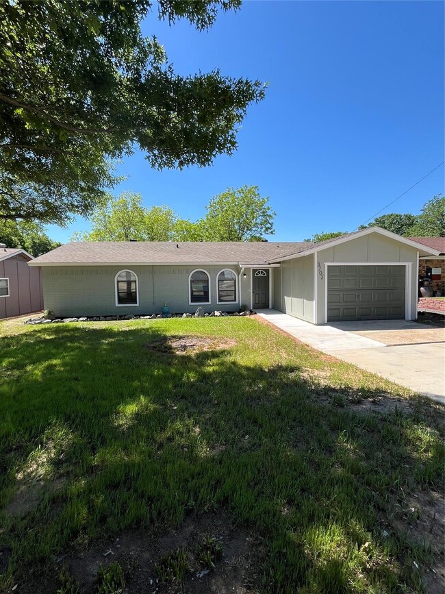 Ranch-style house featuring a garage and a front lawn