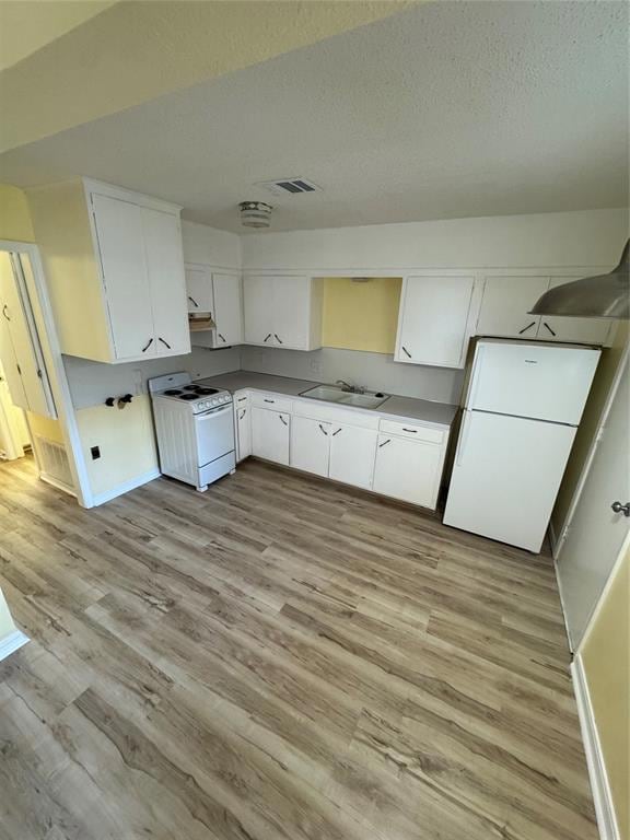 Kitchen featuring stove, refrigerator, light wood-style floors, white cabinetry, and a textured ceiling