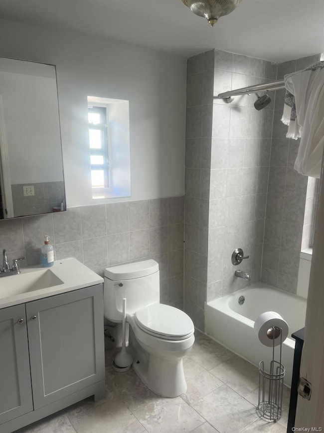 Bathroom featuring vanity, bathtub / shower combination, and tile walls