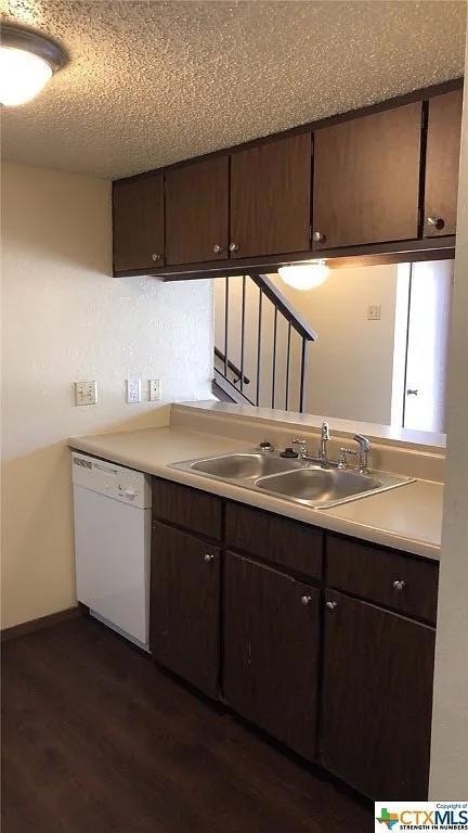 Kitchen with white dishwasher, a sink, dark wood-