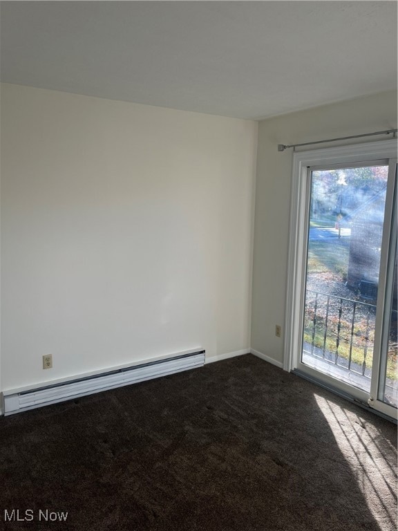 Unfurnished room featuring baseboard heating and dark carpet